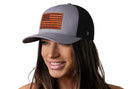 A woman wears the Haka Hat American Flag Trucker Hat, a gray and black USA snapback with a leather flag patch from Haka Hat.