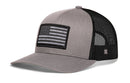 The Haka Hat American Flag Trucker Hat features solid gray front panels, a black mesh back, and a dark monochrome American Flag patch—making this Gray-Black USA Tactical Snapback perfect for showing your style.