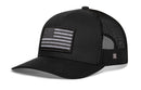 The Haka Hat American Flag Trucker Hat is a black snapback with a mesh back, curved brim, grayscale embroidered flag patch on the front, and a small logo tag. This USA Tactical hat is by Haka Hat.