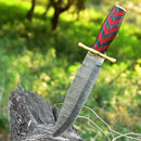 The Texan Knives Antique Damascus Steel Bowie Knife – 11" with Brass Guard and Pakka Wood Handle is embedded vertically in a weathered tree stump, set against a blurred green forest background.