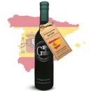 A bottle of Georgetown Olive Oil Co. Green Arbequina (SPAIN) Extra Virgin Olive Oil, featuring a brown tag, stands before an outline of Spain’s map and flag. The tag highlights that it is a first cold pressed olive oil from fresh harvest olives, rich in polyphenols.