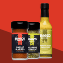 Three Bravado Spice favorites—Garlic & Árbol Seasoning, Jalapeno & Garlic Seasoning, and Creamy Herb & Jalapeno Hot Sauce—stand out against a vibrant red background. Whether you’re looking to power up your Tex-Mex recipes or craft the ultimate brisket rub, each blend bursts with savory roasted garlic notes to amplify any dish.