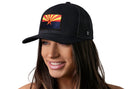 A woman smiles wearing a black Haka Hat Arizona Flag Trucker Hat, a CA Snapback featuring an embroidered Arizona flag patch.