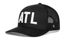 The Haka Hat Atlanta White Block Trucker Hat features a black mesh-back snapback design with bold white ATL letters embroidered on the front.