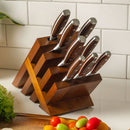 The Messermeister Avanta Pakkawood Knife Block Set - 10 Piece, featuring stainless steel knives with brown handles, is displayed on a kitchen counter near a cutting board with vegetables and a white tile backsplash.