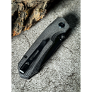 A closed Spaceman Knives N1 EDC with a textured black Micarta handle rests on a rough gray stone surface beside a piece of bark.