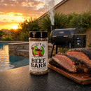 A container of BuffalowBBQ Beef Bark BBQ Rub next to a sliced smoked brisket with dark bark on a cutting board, with a smoker and a swimming pool at sunset in the background.