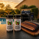 Two bottles of BuffalowBBQ Beef Bark BBQ Rub sit next to a wooden cutting board with sliced, smoked brisket, with a grill and a backyard pool in the background at sunset.