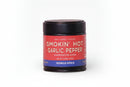 A small jar labeled World Spice Smokin’ Hot Garlic Pepper displays a red label with white text, describing this handcrafted blend by World Spice as a grill seasoning bursting with heat, smoky notes, and citrusy flavors.
