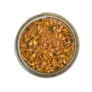 Top view of a glass jar filled with Saltopia BLT Salt: BACON. LETTUCE. TOMATO. by SALTOPIA Infused Sea Salts, showcasing coarse sea salt with visible dried herbs, spices, and chopped garlic pieces on a white background.