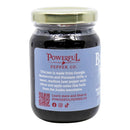 A glass jar of Powerful Pepper Company’s Blueberry Manzano Chili Jam, featuring a light blue label that highlights its blend of blueberries and Manzano chili peppers with citrus and apple notes; the label also displays a QR code and the company website information.