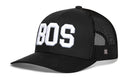 The Haka Hat Boston White Block Trucker Hat is a black snapback featuring white BOS embroidery on the front and a small H logo on the mesh side, offering classic style and a comfortable fit.