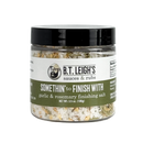 A clear plastic jar of B.T. Leigh’s Garlic & Rosemary Finishing Salt with a black lid and a label featuring the product name and net weight.