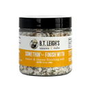 A clear plastic jar of B.T. Leigh’s Thyme & Lemon Finishing Salt with a black lid and a white and yellow label.
