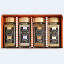 The Spice Wheel Baking Botanicals Gift Set – Anise, Clove, Fennel & Lavender features four elegantly labeled jars of anise seed powder, lavender powder, clove powder, and fennel seed powder. Each aromatic spice is presented in a jar with a gold lid and sleek black label, all neatly arranged in a vibrant orange tray—perfect for adding floral flair to your baking creations.