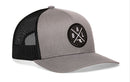 The Haka Hat Baltimore Trucker Hat features a gray-black snapback design with mesh back and a round "BAL X" patch, ideal for fans of classic Baltimore trucker hats.