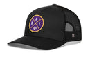 The Haka Hat Baltimore Trucker Hat is a black mesh snapback with a curved brim and a front round purple and gold patch showing crossed lines with B, A, L letters and a small white bison logo at the center.