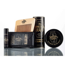 Grooming products from The Immaculate Beard—including the Immaculate Fast Absorbing Beard Oil For Men Softens Skin, beard balm, beard wash, a wooden comb, and a peppermint lip balm—are arranged on a reflective surface for superior beard conditioning.