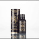 A black bottle of The Immaculate Beard Immaculate Fast Absorbing Beard Oil For Men Softens Skin, a natural beard oil from The Immaculate Beard, rests next to its cylindrical packaging—marked with scent notes of tobacco blossom, caramel, rose, and honey—against a white background.