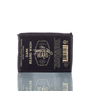 A black bar of The Immaculate Beard’s Immaculate Beard Natural Wash Bar For Men Deep Clean, featuring scents of tobacco blossom, caramel, honey, and rose. The packaging showcases detailed product information and a premium grooming supply logo, highlighting its role as an activated charcoal beard cleanser for a refreshing and thorough clean.