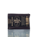 A black, rectangular bar of The Immaculate Beard’s Immaculate Beard Natural Wash Bar For Men Deep Clean is shown with product details, ingredients, and a barcode on the packaging, photographed against a white background with a subtle reflection. This natural beard wash bar uses an activated charcoal formula to deeply cleanse and refresh facial hair.