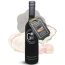 A bottle of Georgetown Olive Oil Co. Black Truffle & Garlic Oil with a tag, placed in front of a garlic bulb and black truffle slices. The bottle features a black cap and displays the white Georgetown Olive Oil Co. logo.