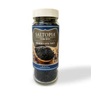 A clear jar labeled SALTOPIA Infused Sea Salts Black Lava Salt features coarse Hawaiian sea salt rich in activated charcoal, with a wooden bowl image on the front label and a white lid.