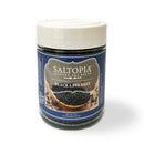 A clear jar of Saltopia Black Lava Salt by SALTOPIA Infused Sea Salts with a white lid and blue label reveals black crystals inside. The label displays "Infused Sea Salts" and an image representing the salt.