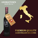 A bottle of Georgetown Olive Oil Co. BOURBON MAPLE Balsamic Vinegar, barrel aged in Modena, Italy, is displayed beside a gold map of Italy and the words: Premium Quality Aged Italian Balsamic.