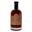 A bottle of Under The Bark Syrup Co Bourbon + Cinnamon Maple Syrup—100% pure maple syrup with cinnamon and bourbon, in a clear glass bottle with a brown maple leaf label.
