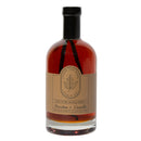 A glass bottle of Under The Bark Syrup Co Bourbon + Vanilla Maple Syrup, labeled 100% pure with a beige label, maple leaf logo, and black wax seal—ideal as a gourmet gift.