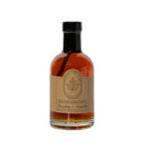 Under The Bark Syrup Co Bourbon + Vanilla Maple Syrup comes in a clear glass bottle with a black cap and light brown label featuring a leaf logo—100% Pure Maple Syrup, perfect as a gourmet gift for any occasion.