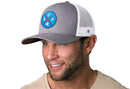 A man wears a Haka Hat Buffalo Trucker Hat, Gray-White Snapback, with a blue and red BUF X patch featuring a New York State silhouette.