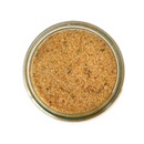 Top view of a glass jar of SALTOPIA Infused Sea Salts' BUMPIN' CHICKEN & DUMPLINS—Chicken and Herbs Seasoning—a light brown, finely ground blend with green and brown flecks, ideal for enhancing comfort food dishes.