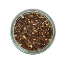A glass jar of SALTOPIA Infused Sea Salts' Saltopia Smoky Blended Salt: BURGER BUDDY, featuring a coarse mix of dried herbs, smoked alderwood sea salt, and chunky seasoning pieces, viewed from above on a white background.