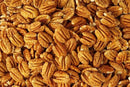 A close-up of Millican Pecan Orchard Fresh Raw Pecan Halves - Premium Shelled Texas Pecans highlights their textured brown surfaces and unique curved shapes.