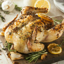 Roast chicken seasoned with SALTOPIA Infused Sea Salts' Saltopia Ultimate Carnivore Salts, lemon slices, and herbs, garnished with rosemary, garlic, and lemon, served on a wooden cutting board.