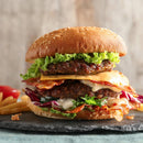 A large double cheeseburger sits on a slate, perfectly seasoned with SALTOPIA Infused Sea Salts from the Saltopia Kitchen Favorite Flavors Gift Set: COOKS SURVIVAL KIT; fries and ketchup are in the background.