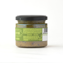 A glass jar with a black lid contains Taycte Famiglia Crispino Green Olive Bruschetta Spread — Tapenade Style Italian, perfect for those who enjoy authentic Italian bruschetta. The back label displays ingredients and product information in multiple languages on a green background, with a barcode visible on the right side of the label.