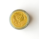 A small glass jar of Taycte Famiglia Crispino Green Olive Bruschetta Spread — Tapenade Style Italian, filled with a coarse, yellow-brown paste and viewed from above on a white background.