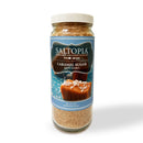 A 16oz glass jar of SALTOPIA Infused Sea Salts Caramel Sugar: DATE NIGHT with a blue label shows caramel pieces topped with salt and the net weight. Labeled as SALTOPIA Gourmet Infused Sugars, Caramel Sugar, DATE NIGHT.