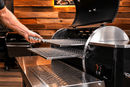 A hand uses a stainless steel Rack Puller™ by Pimp My Grill® to slide a grill grate out of a pellet grill.