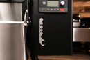 A metal Rack Puller™ by Pimp My Grill® with the word HOT vertically cut into the handle, magnetically attached to the side of a grill’s digital control panel.