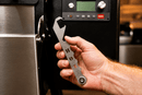 Hand holding a metal Rack Puller™ by Pimp My Grill® with the word HOT cutout along the handle.