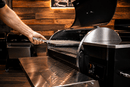 A hand uses a Rack Puller™ by Pimp My Grill® to remove a grill grate from a pellet grill.