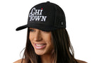 A woman with long brown hair smiles while wearing a Haka Hat Chi Town White Script Trucker Hat, a black Illinois snapback by Haka Hat, featuring white embroidered text against a plain white background.