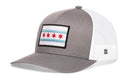 The Haka Hat Chicago Flag Trucker Hat in gray and white features mesh back, snapback closure, and a front patch with the iconic two blue stripes and four red stars.