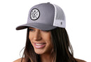 A smiling woman wears the Haka Hat Chicago Trucker Hat in gray and white, featuring a circular CHI X patch design on the front.