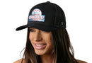 A smiling woman wears the Haka Hat Chicago Windy City Trucker Hat—a black cityscape snapback with a patch reading Windy City Chicago Illinois and featuring red stars and blue accents—against a white background.