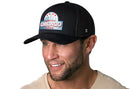 Smiling man wearing the Haka Hat Chicago Windy City Trucker Hat, a black cityscape snapback by Haka Hat, paired with a beige shirt against a white background.